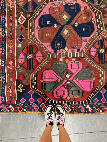 a woman took a picture of her pink shoes and pink rug with floral design